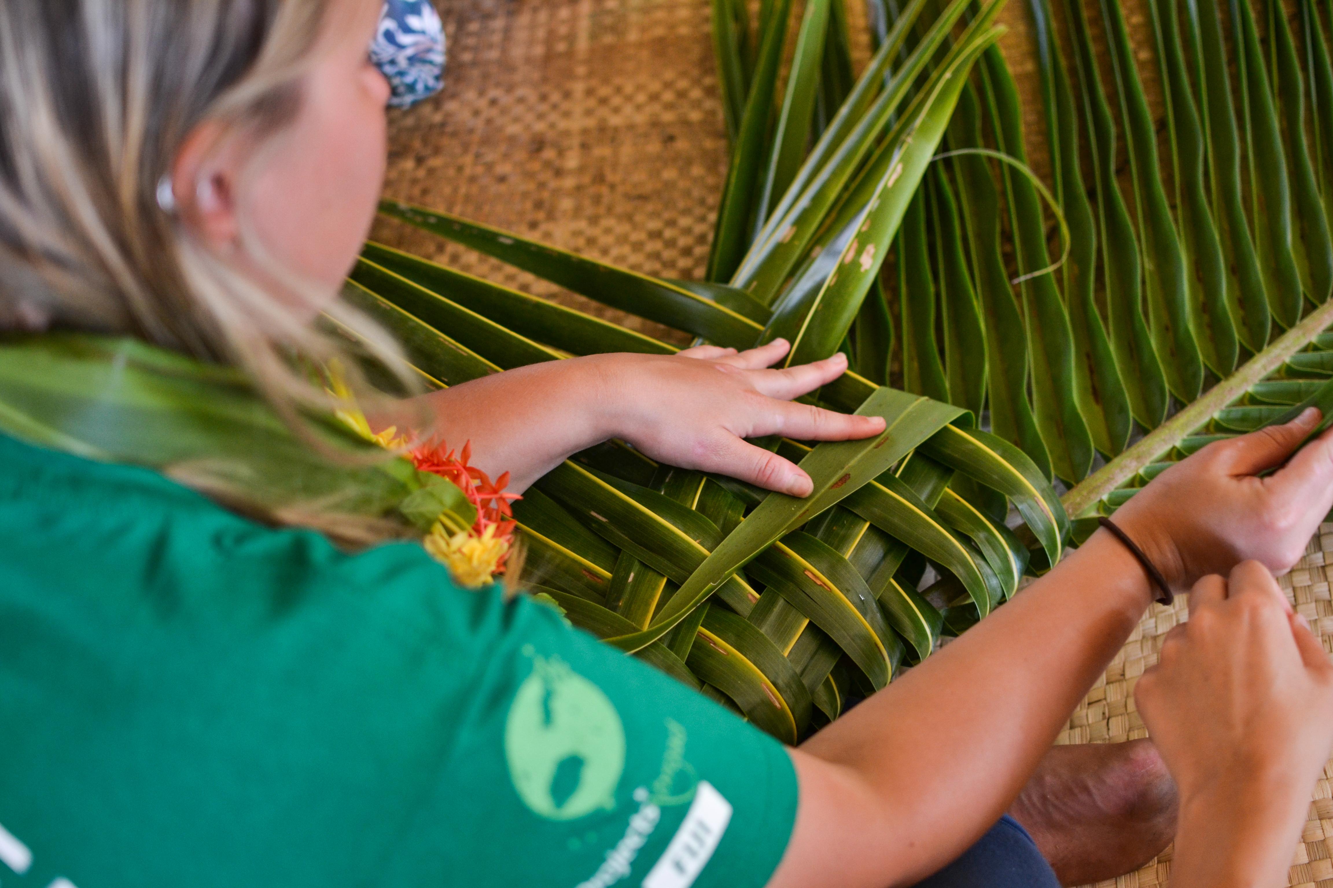 Female Projects Abroad Community Volunteer learning how to weave at a Community Day during Cultural immersion in Fiji Female Culture and Community Volunteer weaves leaves during her volunteering placement in Fiji.